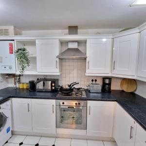 a kitchen with white cabinets and a stove top oven at Pet Friendly 3 Bedroom Apartment in Manchester by Sublime Stays in Manchester