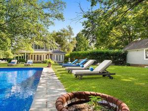 - une rangée de chaises longues à côté de la piscine dans l'établissement Villa Southampton Village, à Southampton