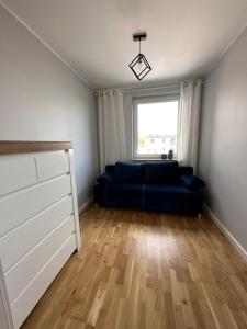 un soggiorno con divano blu e finestra di Apartament a Chełm