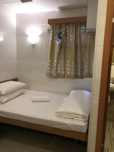 uma cama num quarto com uma janela com lençóis brancos em 香港太阳宾馆 em Hong Kong