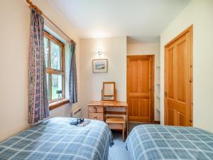 een slaapkamer met 2 bedden, een bureau en een raam bij Cruinn in Taynish