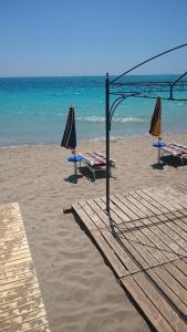 two umbrellas and tables on a beach with the ocean at baia verde appartamento 150 m dal mare in Gallipoli