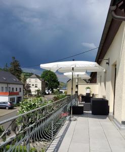 un patio con sombrilla blanca, mesas y sillas en Gästehaus Föhr, en Wintrich