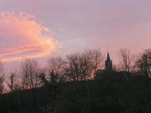 a church on top of a hill with a sunset at Balad'âne in Flachères
