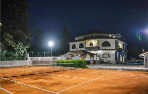 a tennis court in front of a building at night at Cozy Home In Jurdani With Heated Swimming Pool in Jurdani