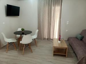 a living room with a couch and a table and chairs at ALMIRIKI Studios & Apartments in Alykes