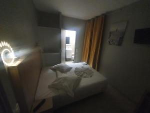 een kleine slaapkamer met een bed en een raam bij Hôtel de Choisy in Parijs
