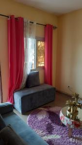 a living room with a couch and red curtains at LNIMMO - DEPOU - Studio meublé Ahmadou Ekie climatisé et avec internet illimité avec forage in Yaoundé