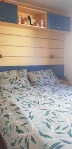 a bed with a blue and white comforter at Splendide mobil-home in Narbonne
