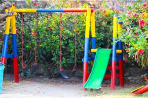 un parque infantil con columpios coloridos en un jardín en Casa del Mar en Tolú