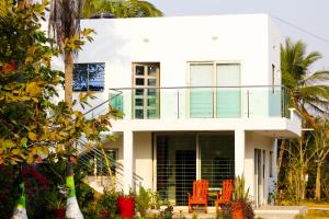 une maison blanche avec des chaises orange devant elle dans l'établissement Casa del Mar, à Tolú