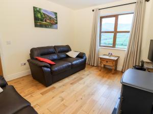 a living room with a leather couch and a window at Number 7 in Lispole