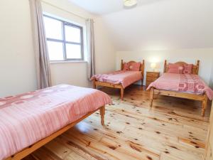 two beds in a room with wooden floors and a window at Number 7 in Lispole
