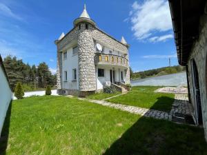 an external view of a large stone house with a grass yard at Къща за гости Замък Никола in Shtarkelovo Gnezdo