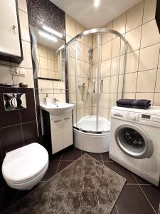 a bathroom with a toilet a sink and a washing machine at Apartament Dąbrowskiego - Gliwice in Gliwice