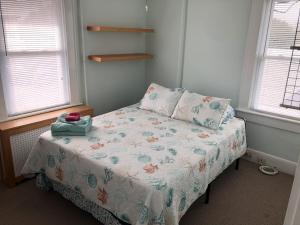 um pequeno quarto com uma cama com um cobertor e 2 janelas em Bay View Bungalow by the Pier home em Norfolk