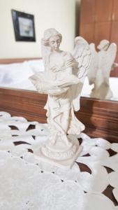 a white angel statue sitting on top of a bed at Liora's Place in Korçë