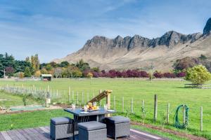 a picnic table and chairs with mountains in the background at River Range Cottage - Havelock North Holiday Home in Havelock North