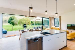 an open kitchen and living room with a large window at River Range Cottage - Havelock North Holiday Home in Havelock North