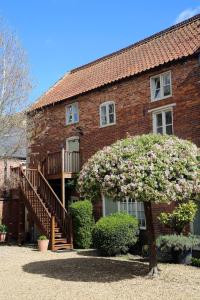 a brick house with a staircase and a flowering tree at The Barn @Bourne Eau House in Bourne