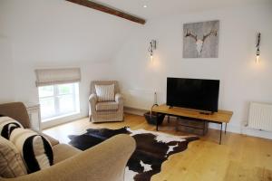 sala de estar con sofá y TV en The Barn @Bourne Eau House, en Bourne