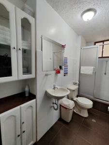 a white bathroom with a toilet and a sink at Apartamento 32 Juana de Arco in Quito