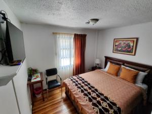 a hotel room with a bed and a television at Apartamento 32 Juana de Arco in Quito