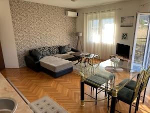 ein Wohnzimmer mit einem Sofa und einem Glastisch in der Unterkunft Porodični Apartman Igalo in Igalo