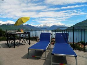 twee blauwe stoelen en een tafel en een parasol op een balkon bij Balcony on Lake Pianello in Pianello Del Lario
