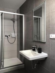 a bathroom with a sink and a shower and a mirror at Pension Drei Rosen in Karlovy Vary