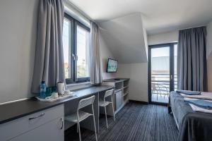 Pokój hotelowy z łóżkiem i biurkiem z krzesłami w obiekcie PIONOW Pokoje Hotelowe - adults only w mieście Krynica Morska