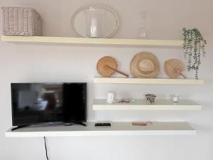 TV de pantalla plana en la parte superior de un estante en APTO. DE 1 DORMITORIO EN PRIMERA LINEA DE PLAYA. ISLA CANELA, en Huelva