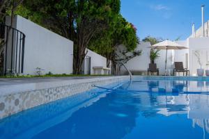 a blue swimming pool with two chairs and an umbrella at Hotel El Farol in Parras de la Fuente