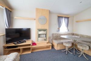 a living room with a flat screen tv and a table at 3 Bed, 8 Berth Caravan For Hire At St Osyth Park Near Clacton-on-sea Ref 28039cw in Clacton-on-Sea