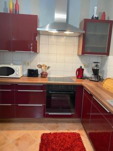 a kitchen with red cabinets and a stove top oven at Ferienwohnung Laura in Bremm