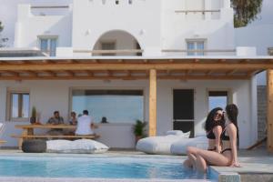 dwie kobiety siedzące na krawędzi basenu w obiekcie Vouno Luxury Villas w mieście Glinado Naxos