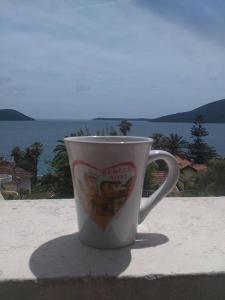 a coffee cup sitting on a table in front of the ocean at Petrovic house in Herceg-Novi