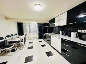 a kitchen with white and black cabinets and a table and chairs at Arshakunyats 88 TopHouse in Yerevan