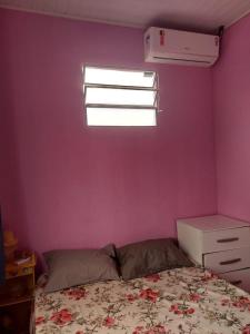 a bedroom with a bed and a purple wall at Casa inteira com AR 2/4 in Salvador