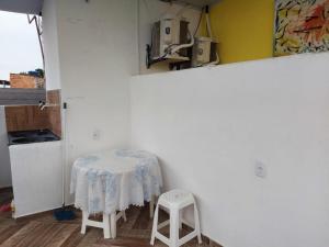 a table and two stools in a white room at Casa inteira com AR 2/4 in Salvador