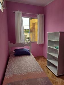 a purple bedroom with a bed and a window at Casa inteira com AR 2/4 in Salvador