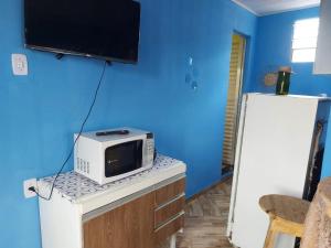 a microwave sitting on top of a counter with a blue wall at Casa inteira com AR 2/4 in Salvador