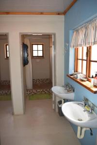 een blauwe badkamer met 2 wastafels en een spiegel bij Waterberg Hideaway in Thabazimbi