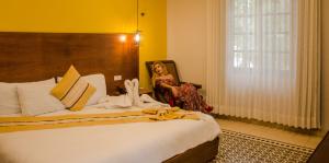 una mujer sentada en una silla junto a una cama en Hotel Marionetas en Mérida