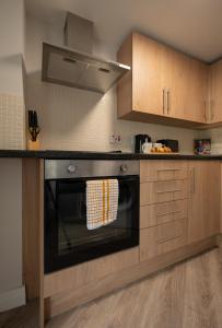 a kitchen with a black oven and wooden cabinets at 3 bedroom Cannock flat ideal for groups in Great Wyrley