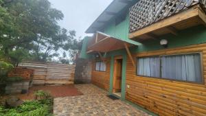 een huis met een houten gevel en een veranda bij Cabañas Manuto Piataro in Hanga Roa