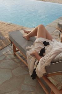 a woman laying on a bed next to a pool at Vouno Luxury Villas in Glinado Naxos