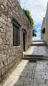 a stone building with a window and a brick sidewalk at Arbe Downtown in Rab