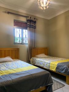 2 camas en un dormitorio con ventana y lámpara de araña en Luxury M Apartments en Kampala