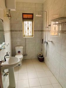 a bathroom with a toilet and a sink and a window at Luxury M Apartments in Kampala